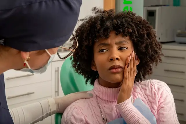 Female patient experiencing toothache, discussing her discomfort with a dentist in a dental clinic during a thorough examination